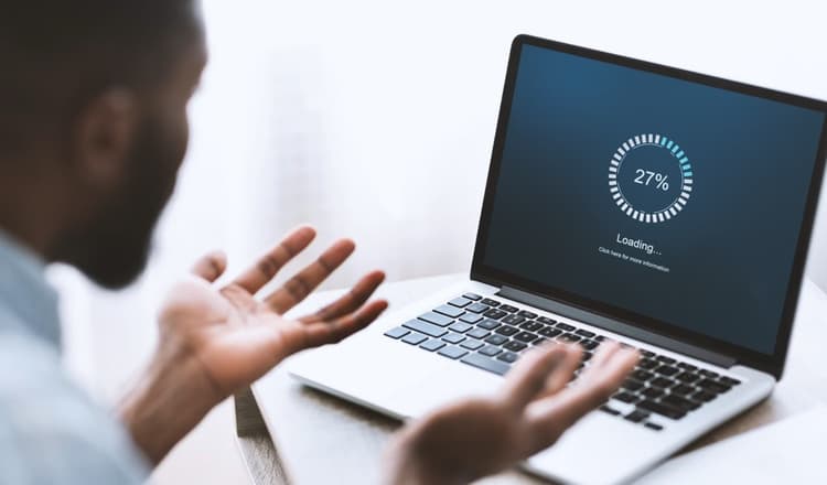 Color image of man watching laptop screen reload very slowly.