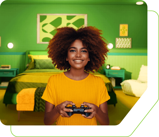 Women holding a controller for a gaming system while smiling at the camera in a bedroom.